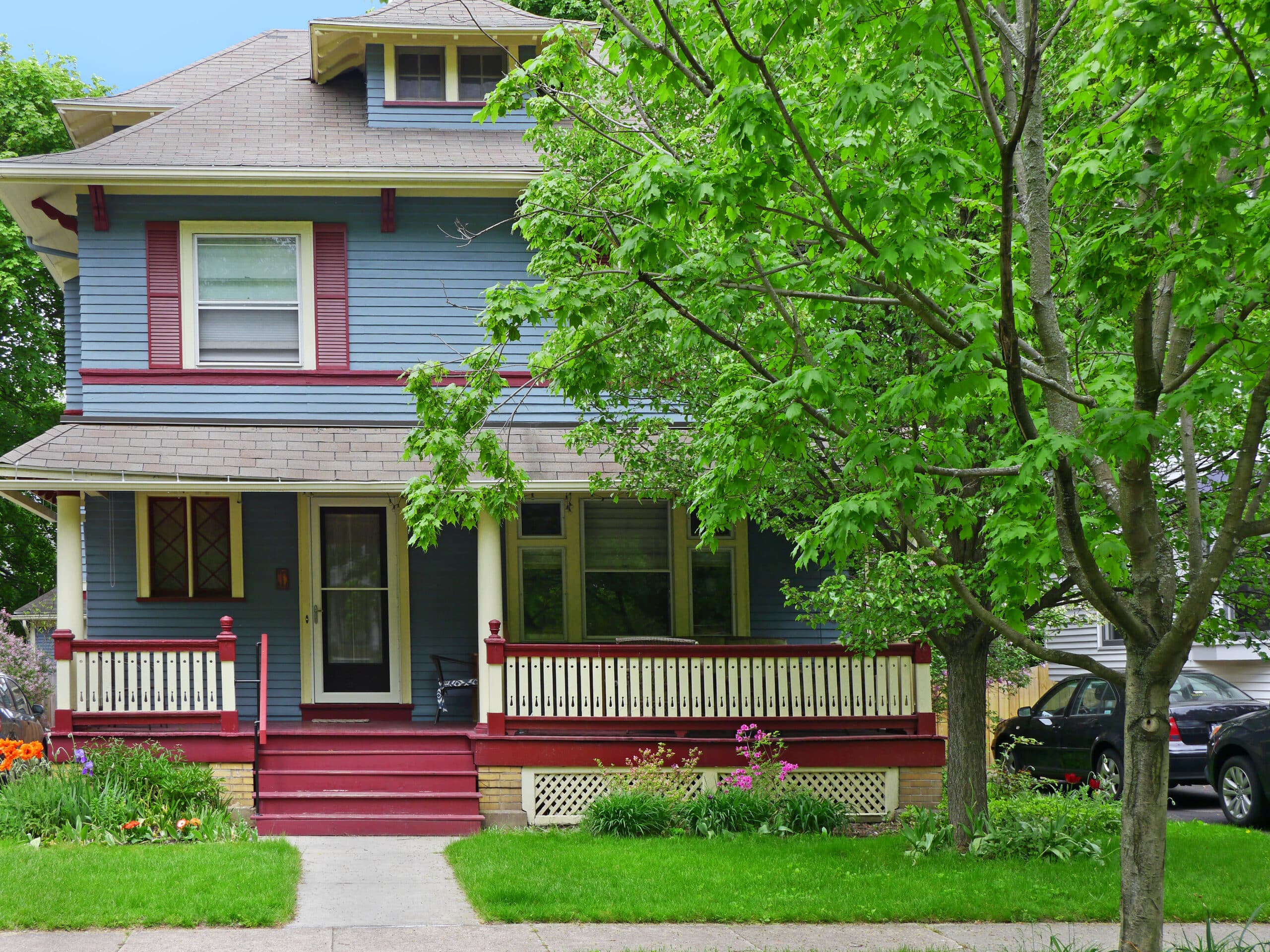 suburban middle class American house with large porch with tree on front of house