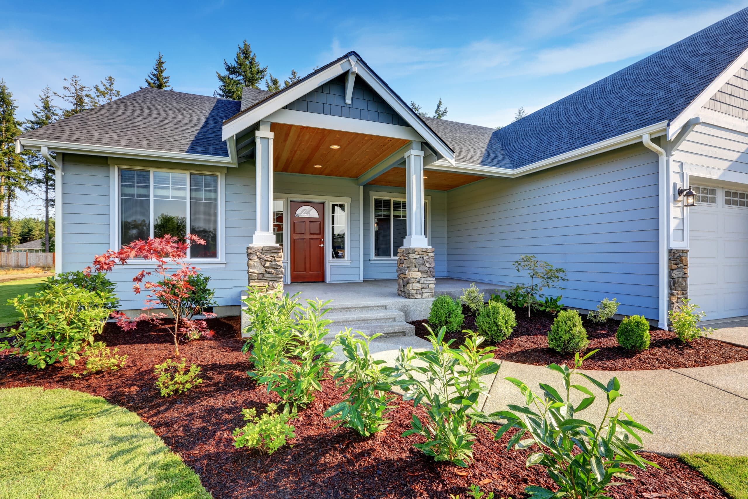 Light blue siding house . Porch with stone base columns and concrete walkway. Northwest, USA