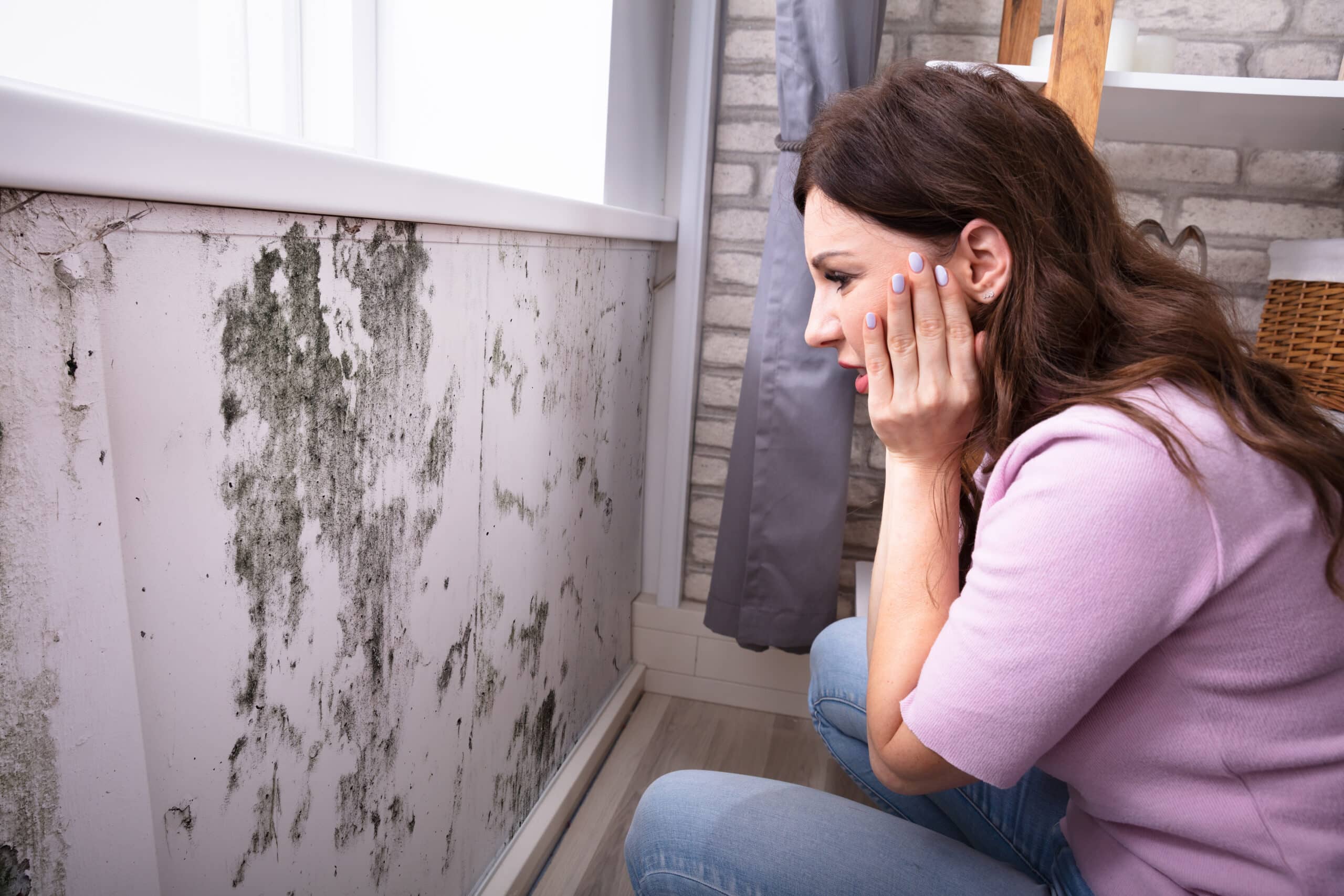 shocked woman looking at mold on wall