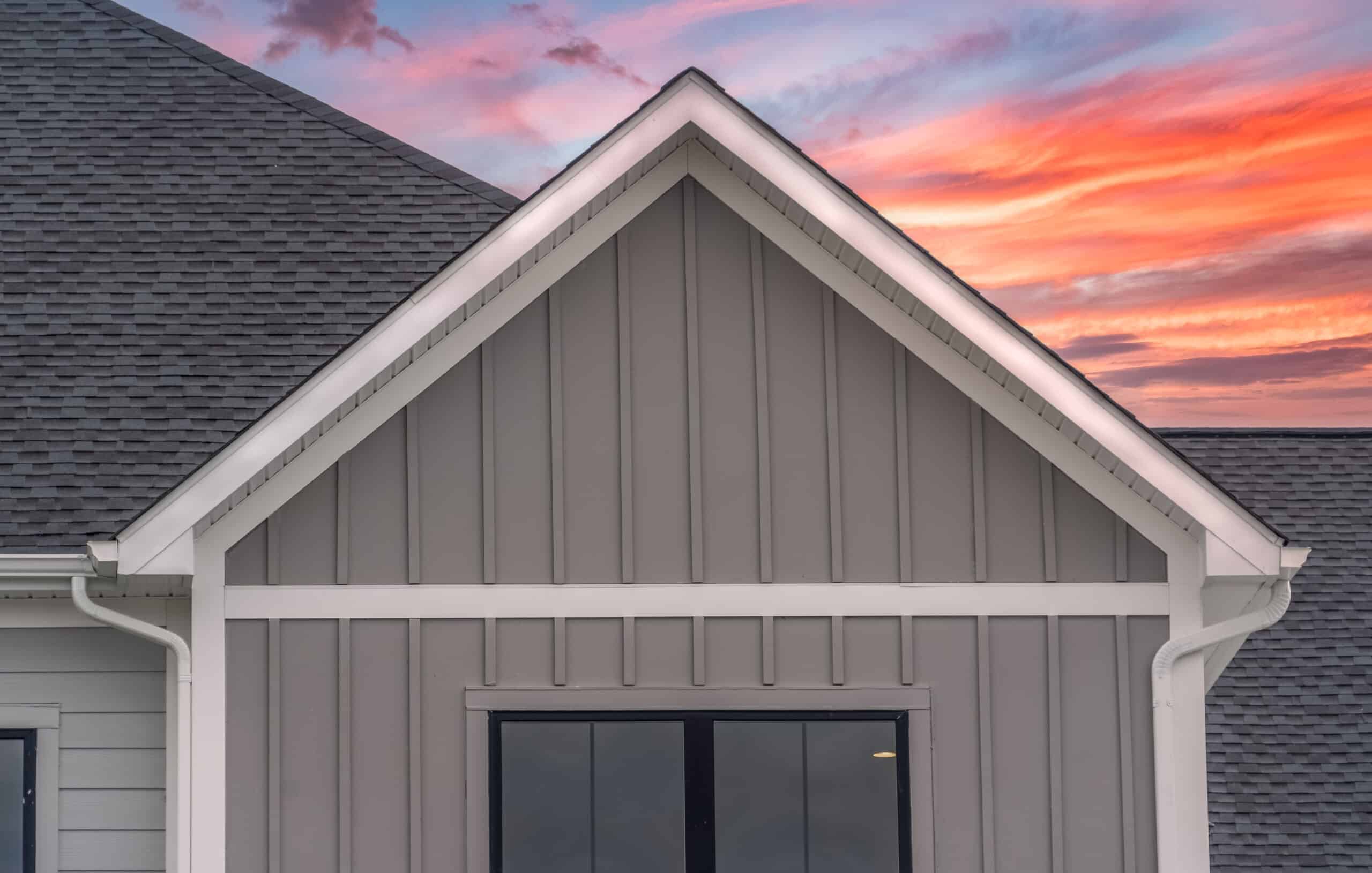 white frame gutter guard system with dark gray horizontal vinyl siding whiet accents fascia soffit on a pitched roof attic at a luxury american single family home