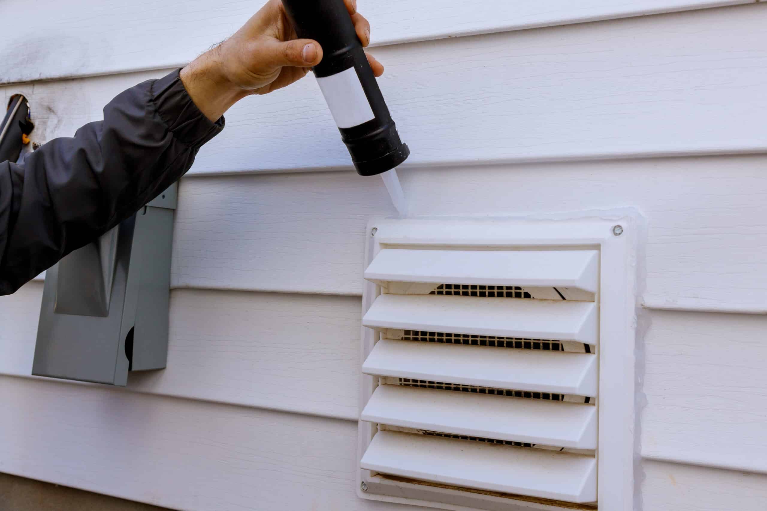 dryer exhaust fan on side of house with plastic white trim with sealant