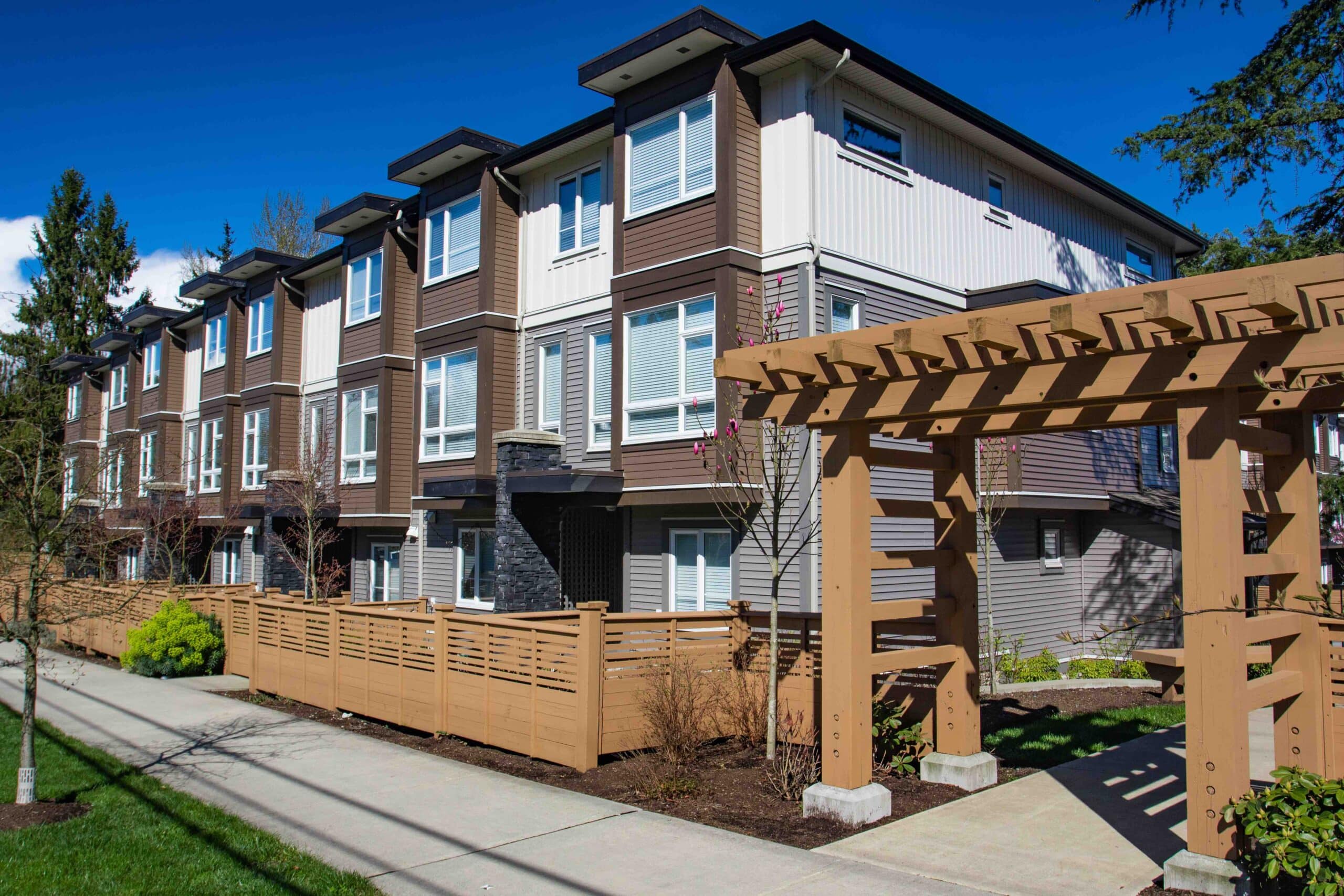 Modern low rise wood frame complex. Brand new apartment building on sunny day in spring with blooming trees.