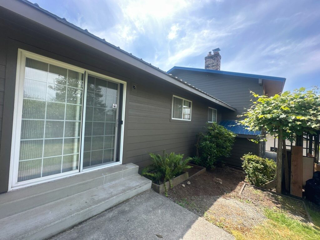 hardieplank siding, large french sliding door with blue sky over house and greenery in the backyard